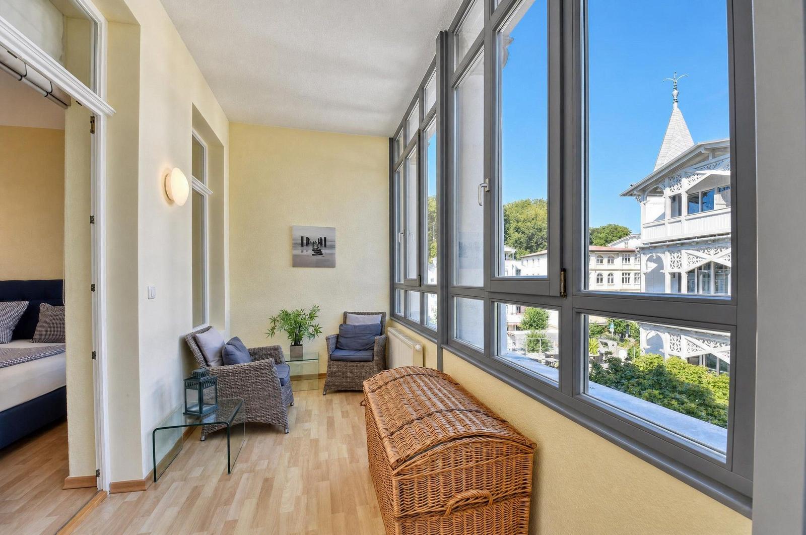 Wohnbereich mit Sitzgelegenheiten und großem Fensterblick auf ein Gebäude.