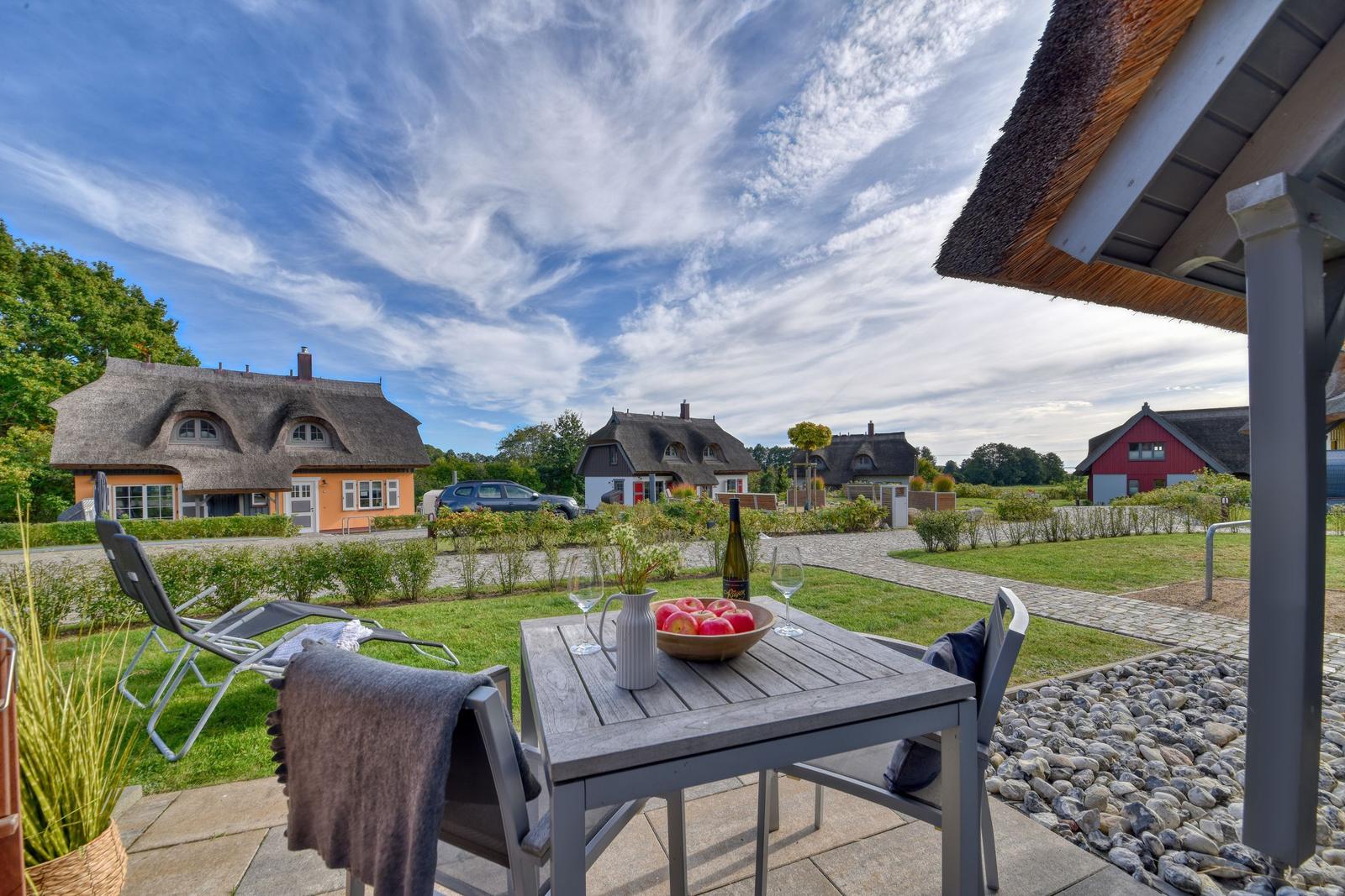 Terrasse mit Tisch, Stühlen und Blick auf traditionelle Häuser mit Strohdächern.