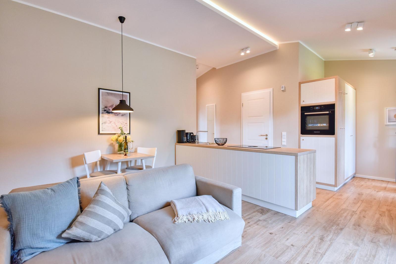 Wohn- und Küchenbereich mit Sofa, Esstisch und integriertem Ofen.