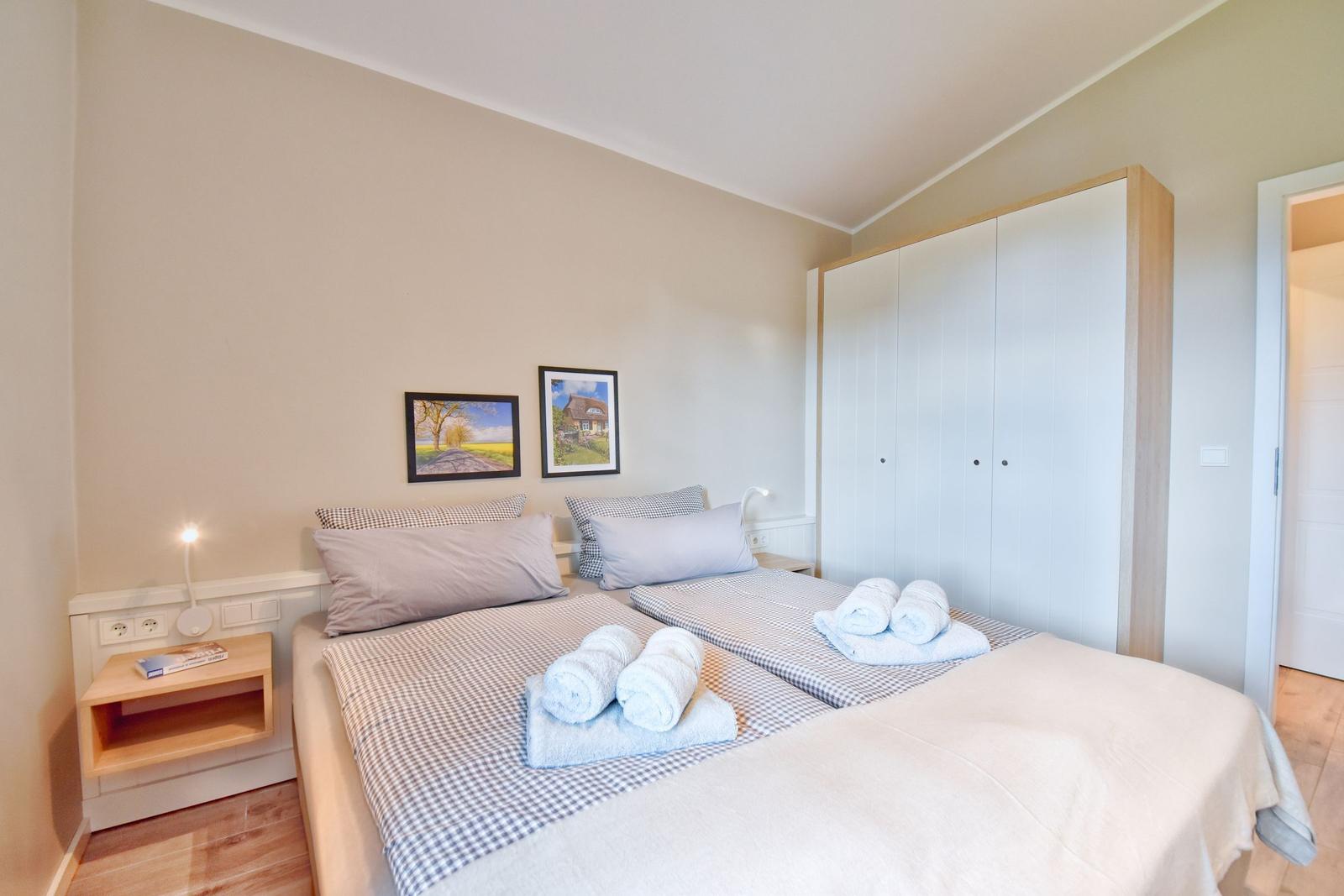Schlafzimmer mit Doppelbett, Kleiderschrank und Nachttisch mit Lampe.