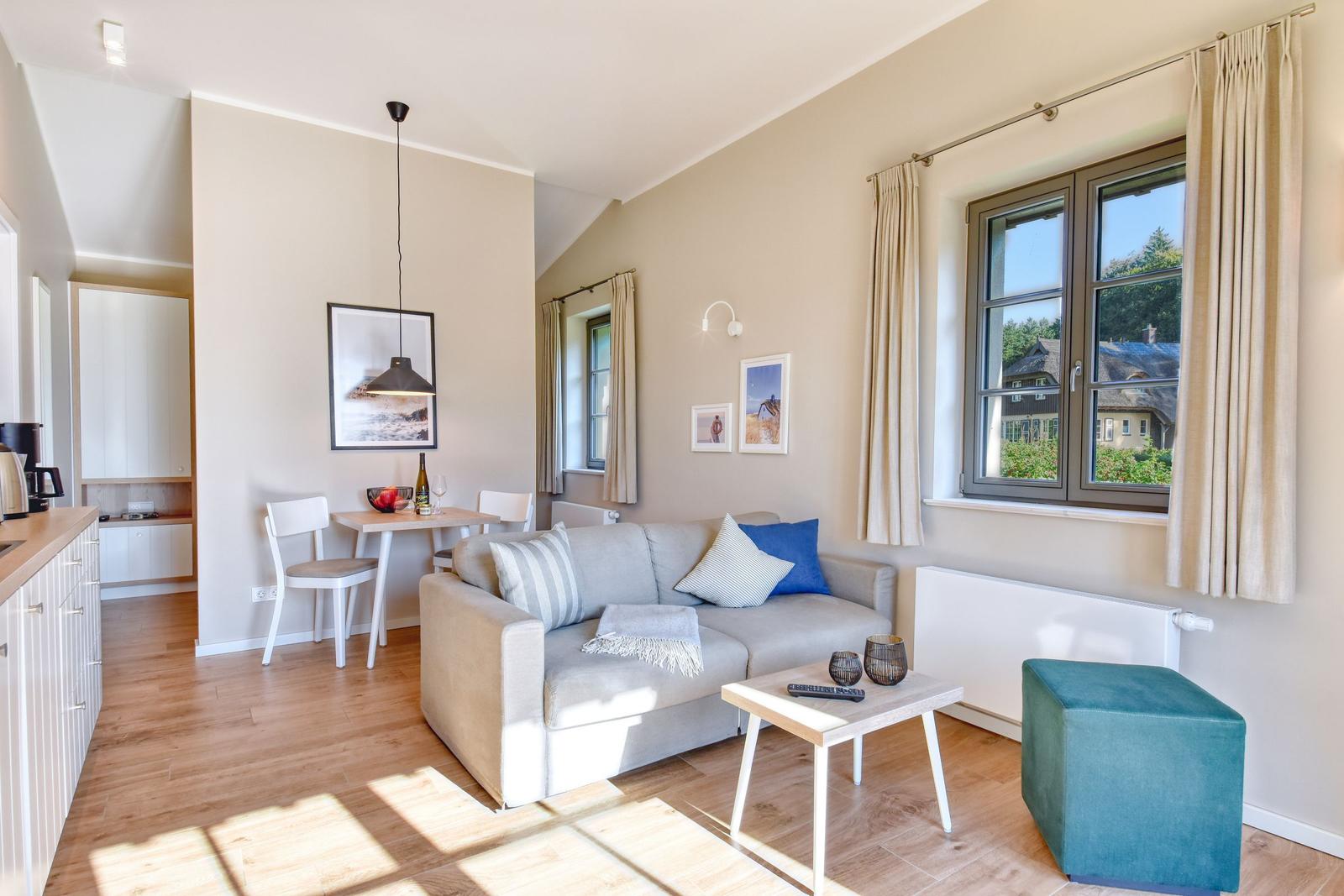 Wohn- und Essbereich mit Sofa, Tisch und Fensterblick auf Dächer.