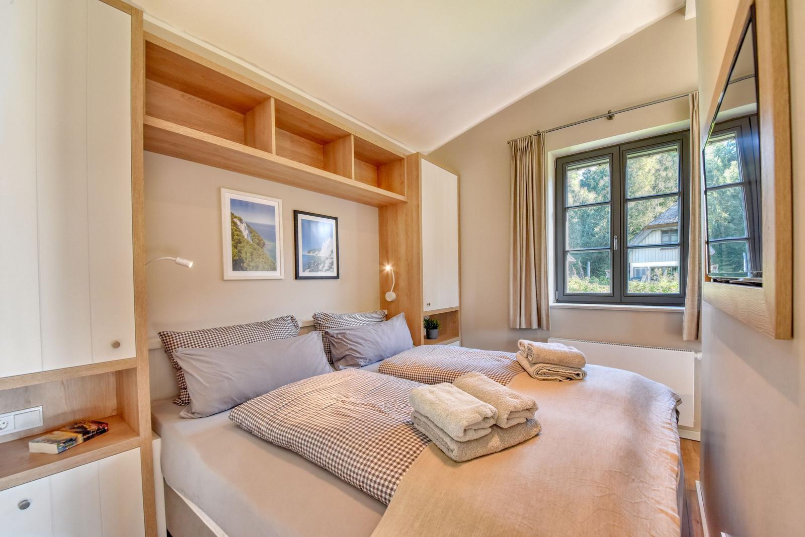 Schlafzimmer mit Doppelbett, Holzmöbeln und Fensterblick auf Garten.