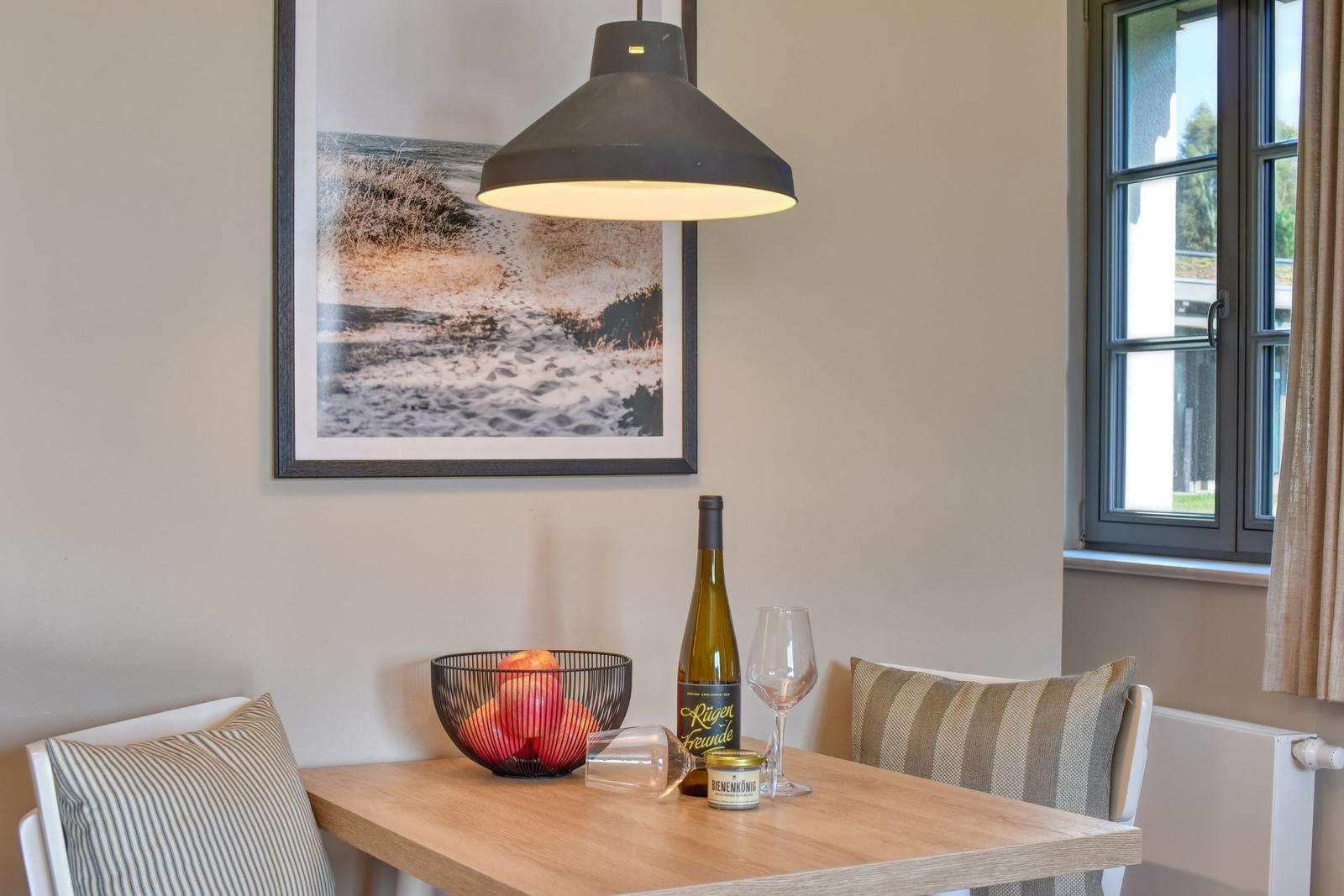 Esstisch mit Stühlen, Weinflasche und Obstschale unter einer Lampe.