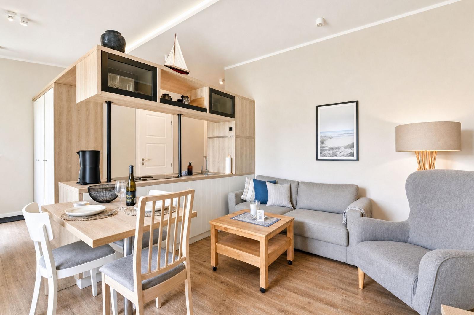Wohn- und Essbereich mit Küchenzeile, Sofa und Stühlen. Holzmöbel und Wandbild.