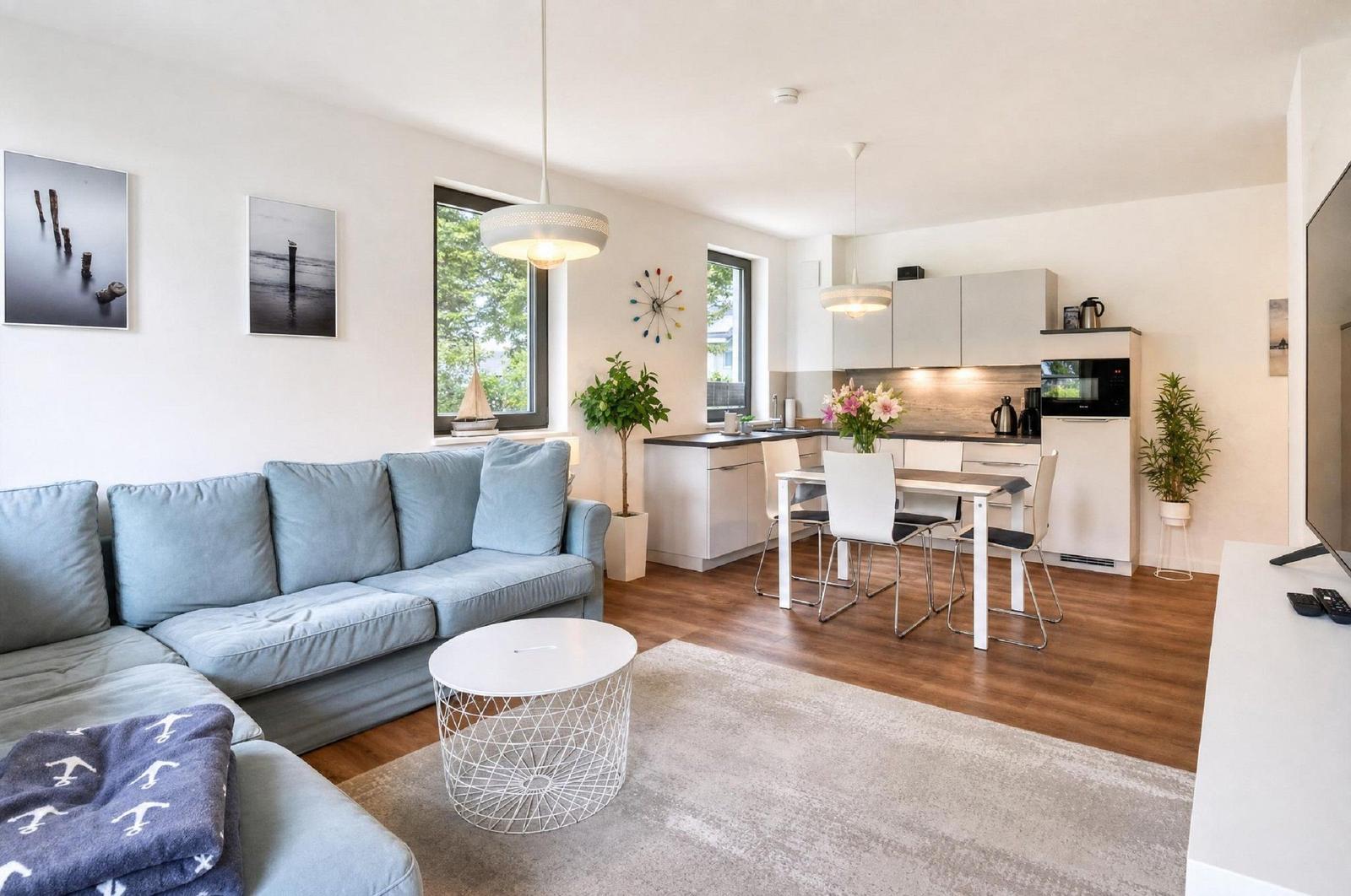 Wohnzimmer mit Sofa, Couchtisch und Blick in die Küche.