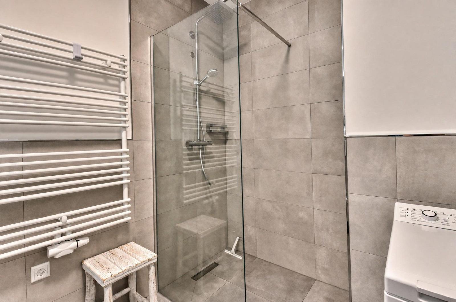 Dusche mit Glaswand, Heizkörper und Waschmaschine