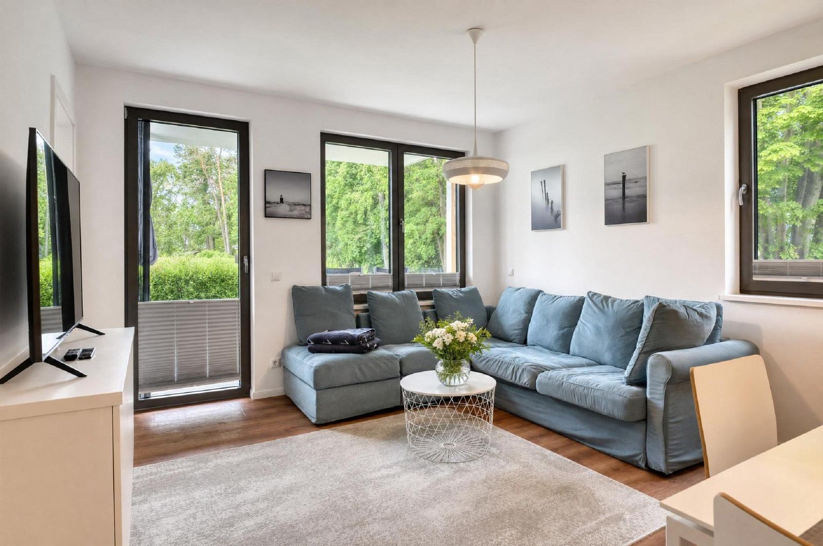 Wohnzimmer mit Sofa, TV und Fenstern zum Garten