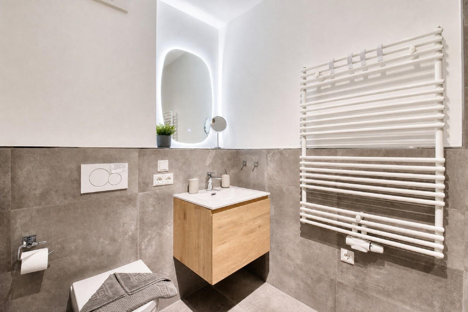 Badezimmer mit Waschbecken, Spiegel und Heizkörper an der Wand.