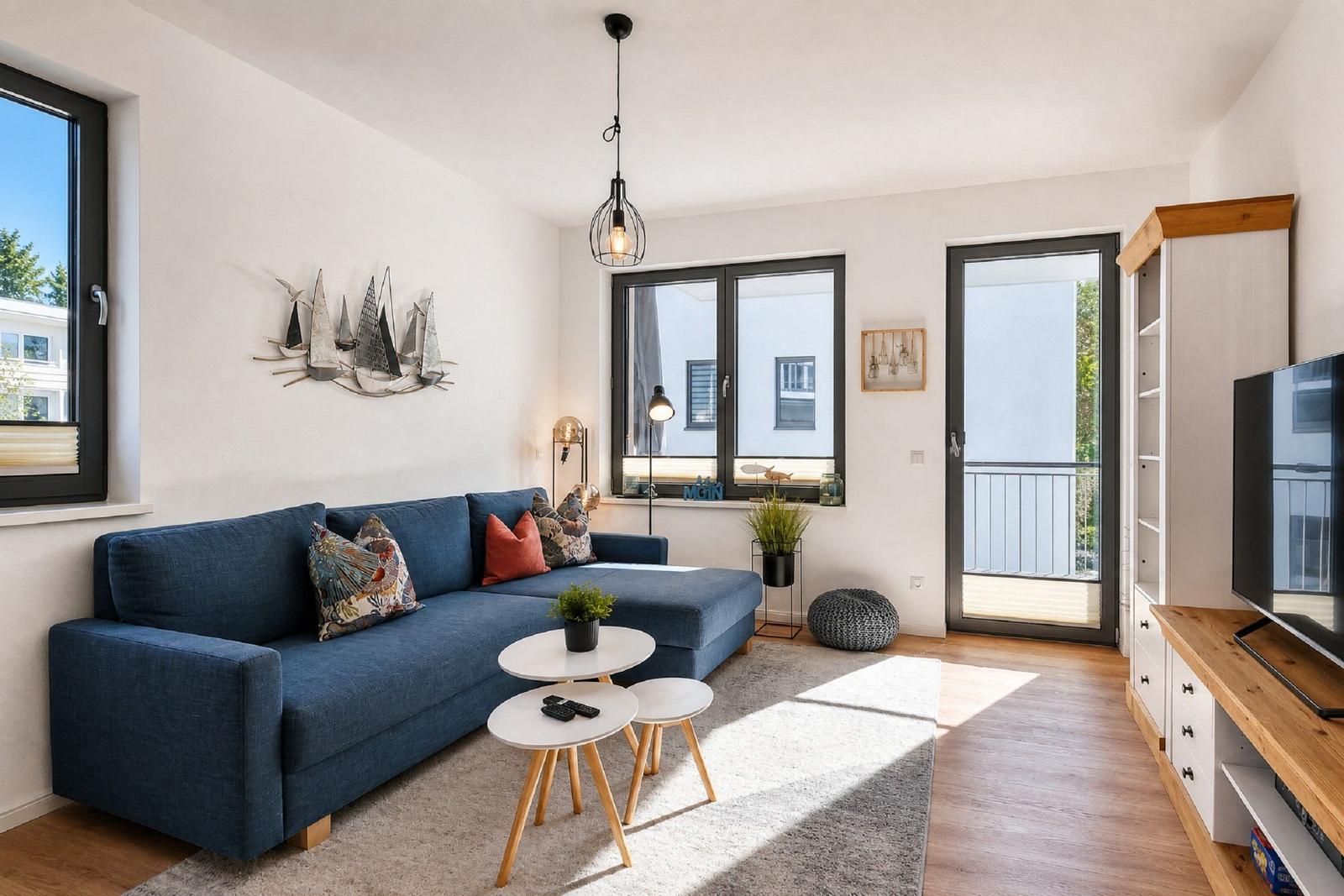Ein Wohnzimmer mit blauem Sofa, zwei runden Tischen und einer TV-Einrichtung.