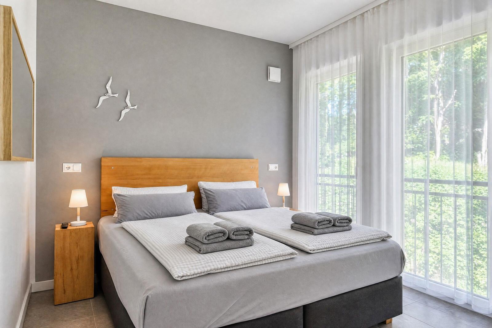 Ein Schlafzimmer mit Doppelbett, Holzgestell und Blick auf einen Garten.