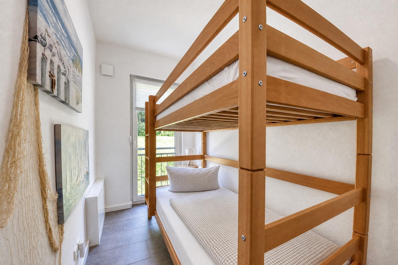Zimmer mit Doppelstockbett, Fenster und Wandbildern.