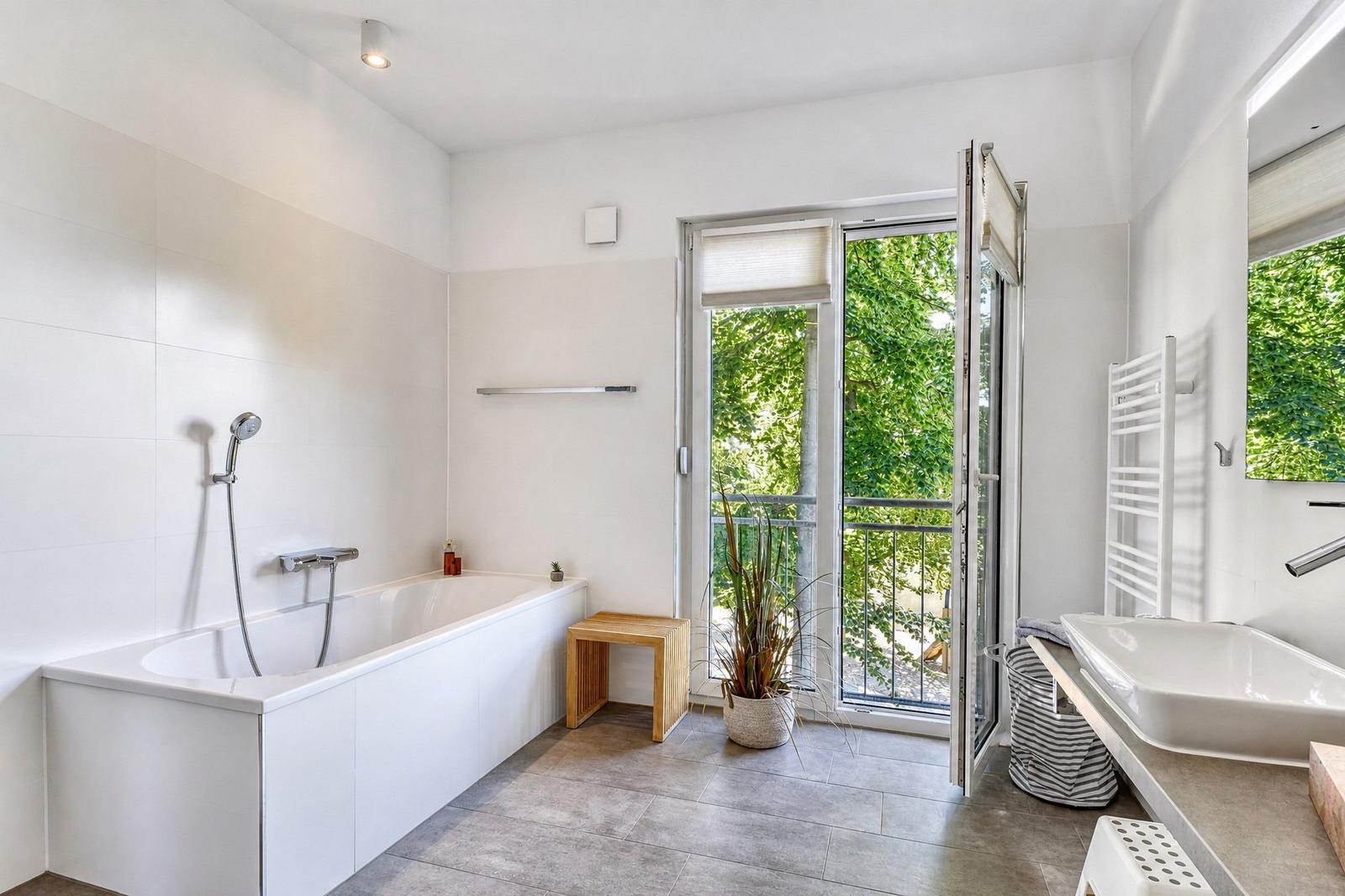 Bad mit Badewanne, Dusche und Balkon mit Blick auf Grün