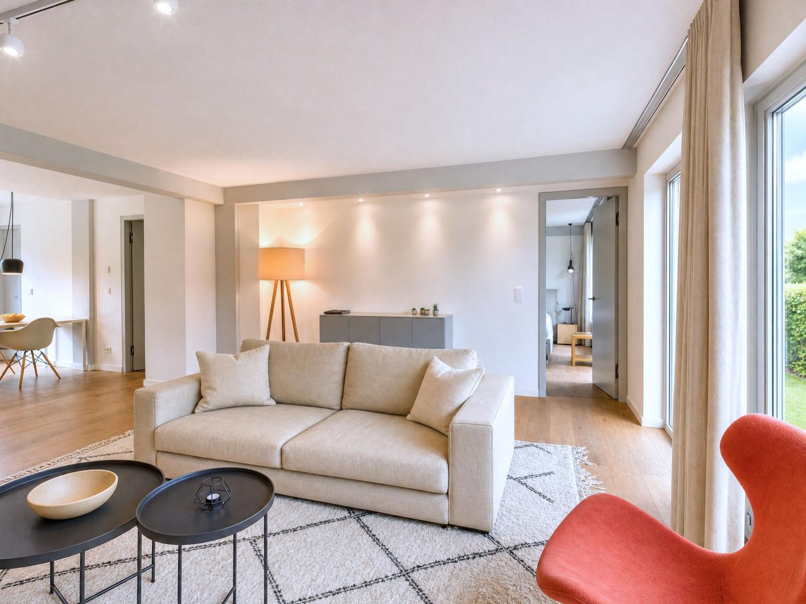 Wohnzimmer mit Sofa, Teelicht, Tisch und Sessel. Durchgang in Schlafzimmer und Küche.