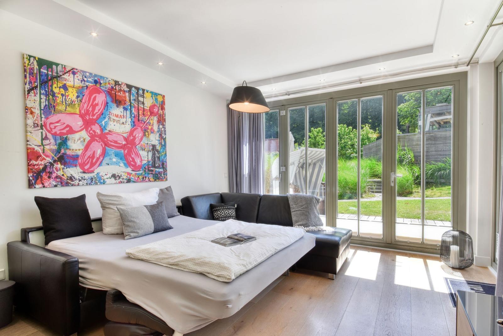 Schlafzimmer mit Schlafcouch, großem Fenster und Wandbild