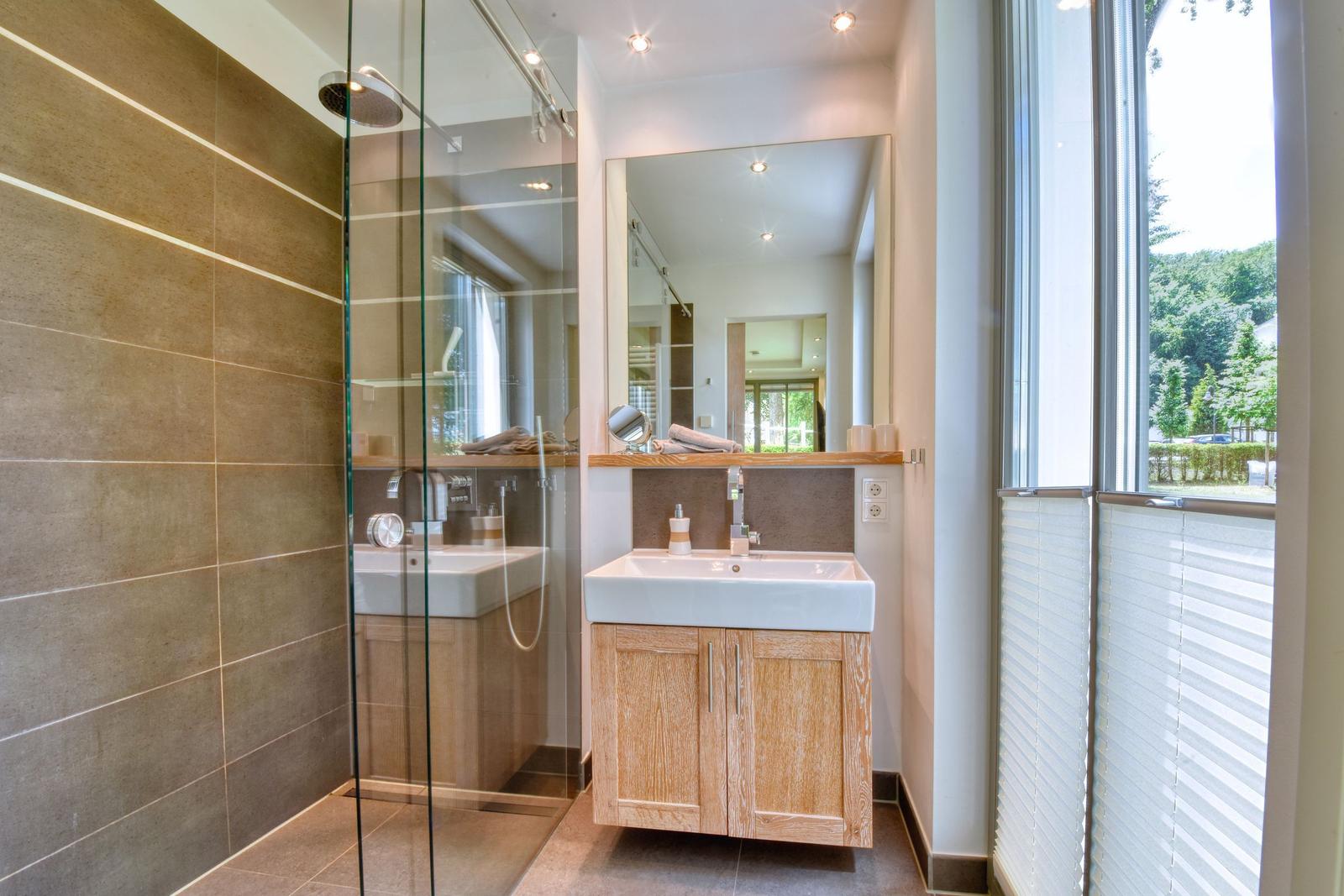 Badezimmer mit Dusche, Waschbecken und Fenster.