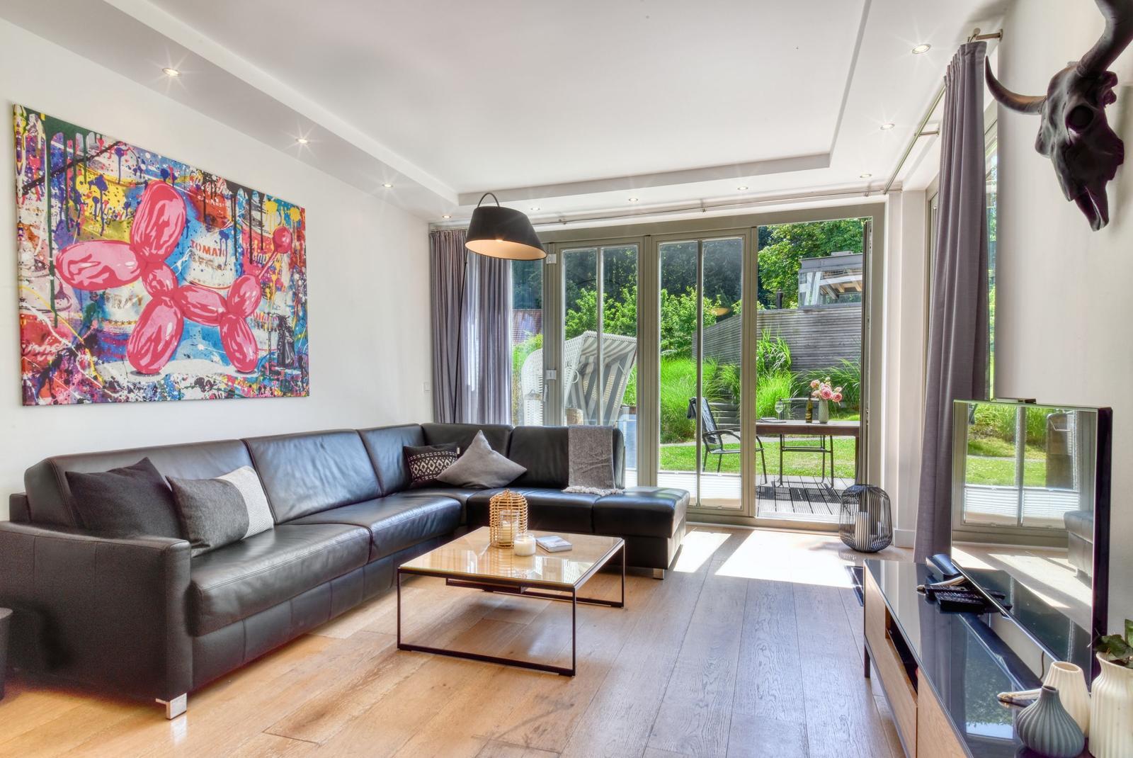 Wohnzimmer mit Ledersofa, Glasfront und Wandbild