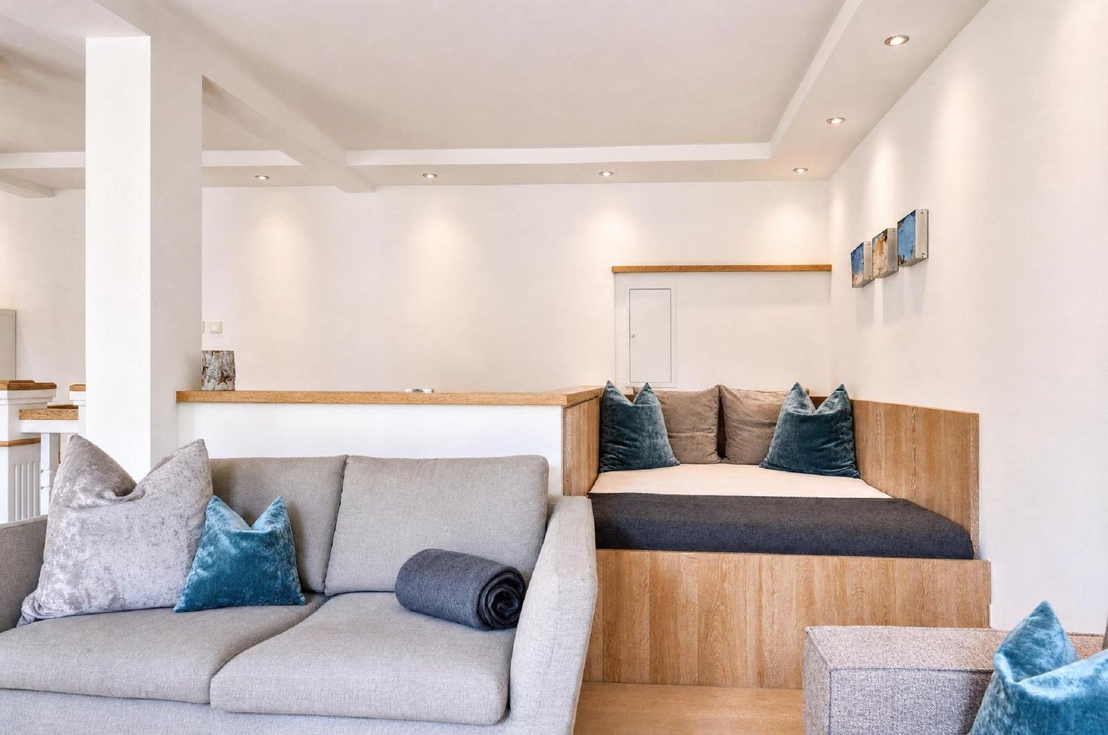 Ein Wohnbereich mit Sofa und integriertem Bett mit Holzrahmen und Kissen.