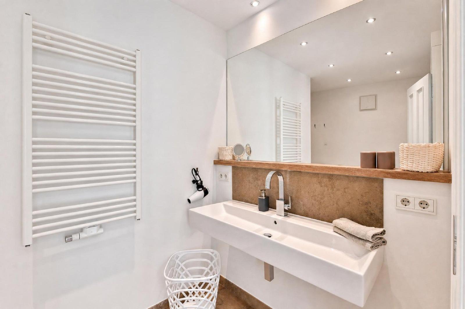 Badezimmer mit Waschbecken, Spiegel und Heizkörper an der Wand.