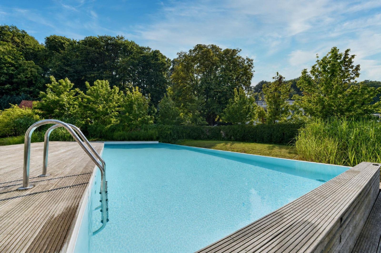 Pool mit Holzterrasse und Blick auf grüne Bäume