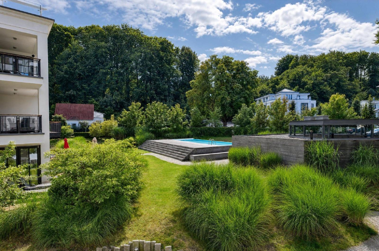 Poolbereich mit Terrasse und grüner Umgebung