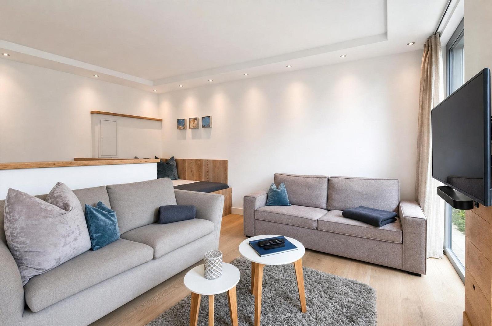 Wohnzimmer mit zwei Sofas, kleinem Tisch und Fernseher an der Wand.