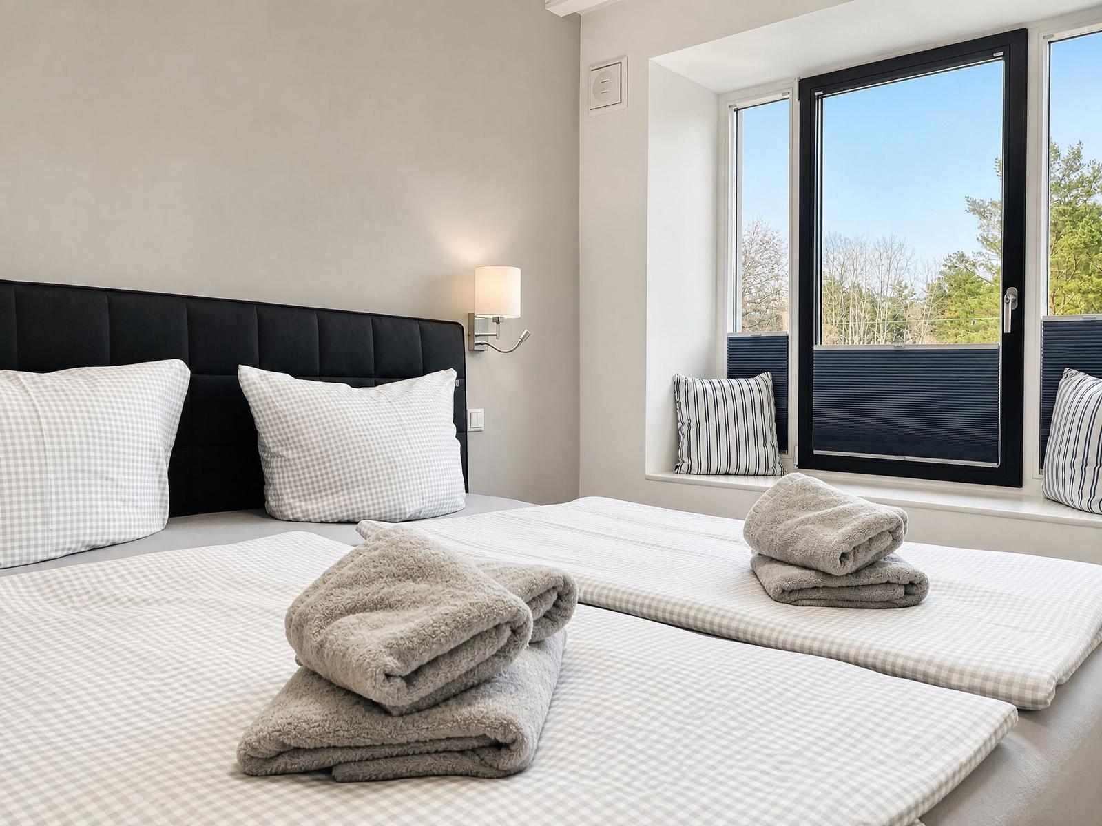 Bedroom with double bed, window, and towels.