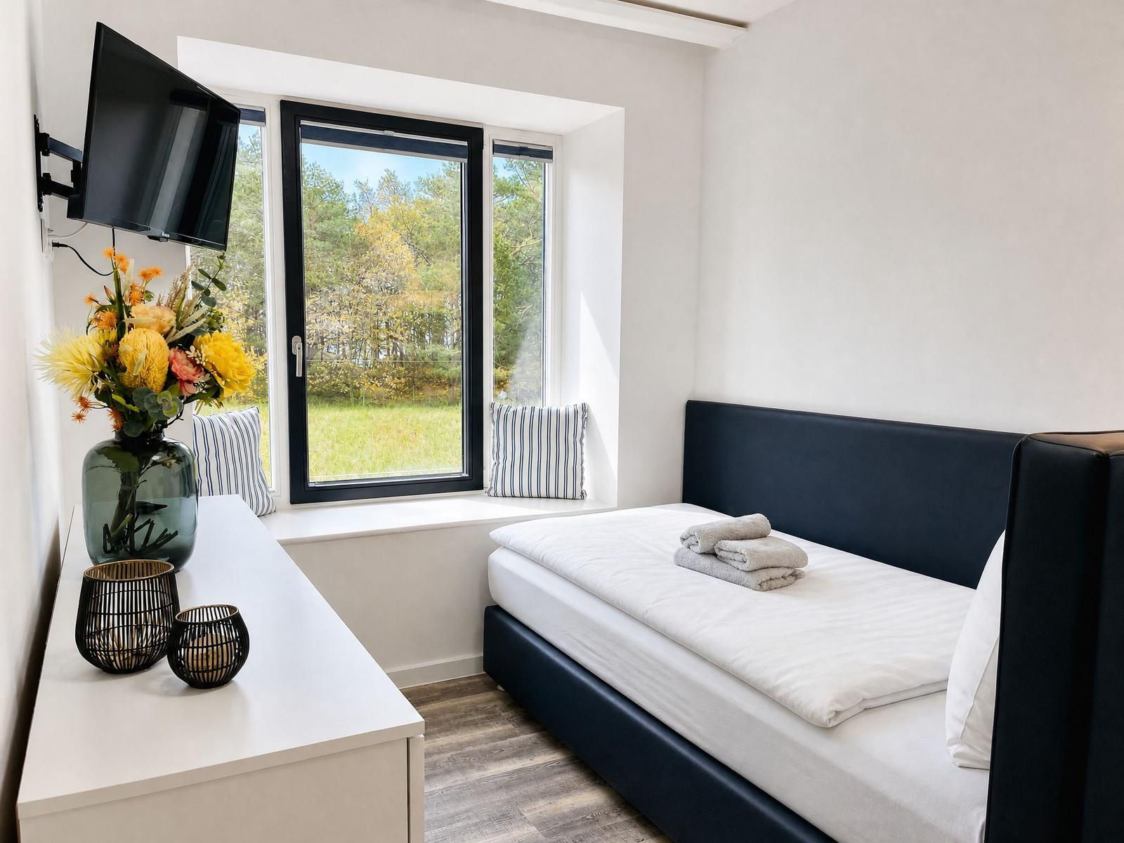 Bedroom with bed, window, and TV. Pillows are on the windowsill.