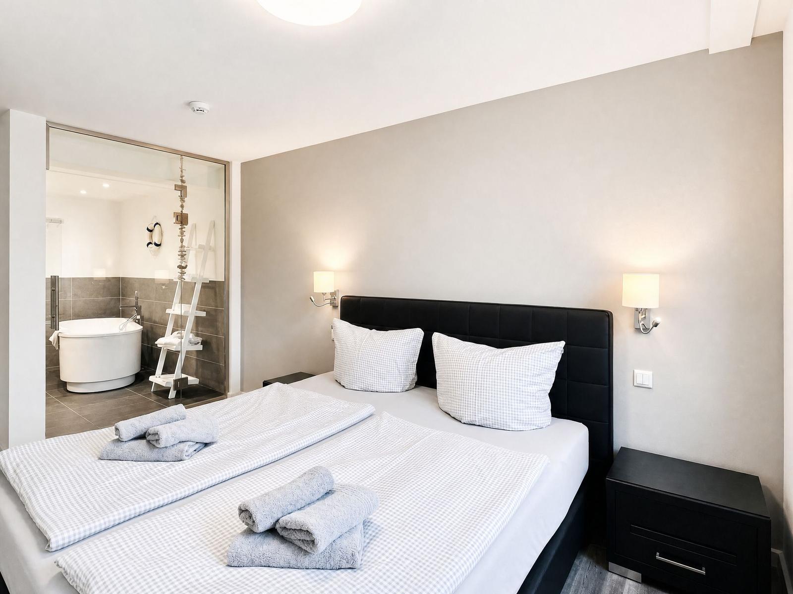Bedroom with double bed and adjoining bathtub