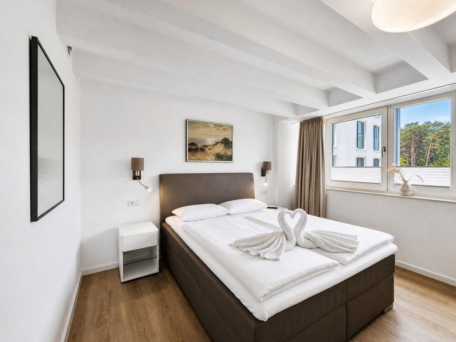 Schlafzimmer mit Doppelbett, Fensterblick und Handtuchschwanen