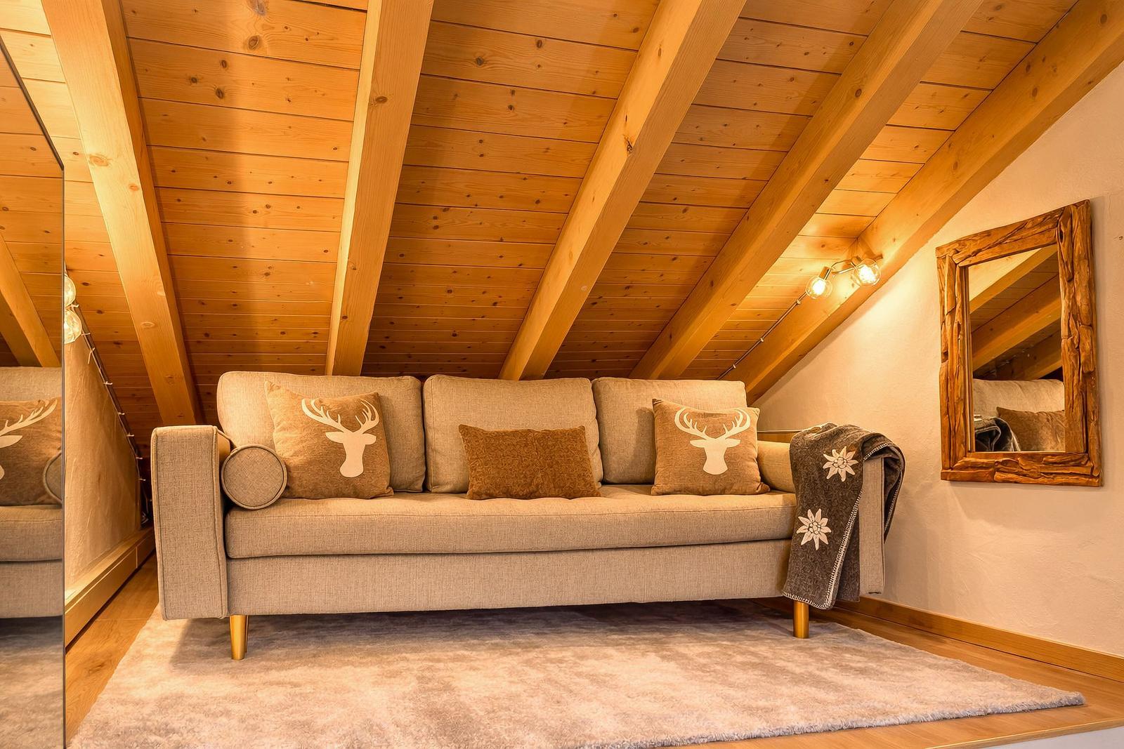 Ein Sofa mit Kissen und Decke unter Holzdecke mit Balken.