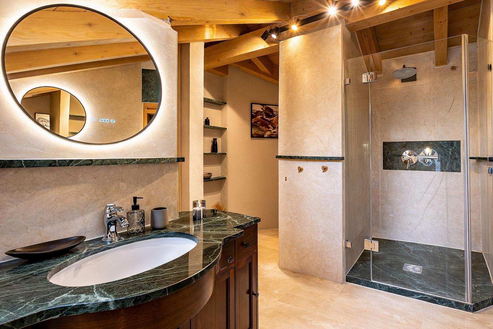 Badezimmer mit Dusche, Waschbecken und Spiegel. Holzdecken und Marmorflächen.