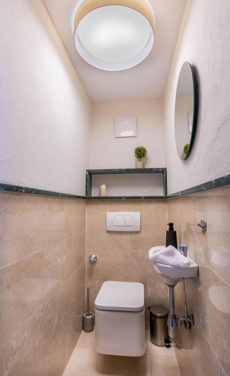 Badezimmer mit Toilette, Waschbecken und runden Spiegel an der Wand.