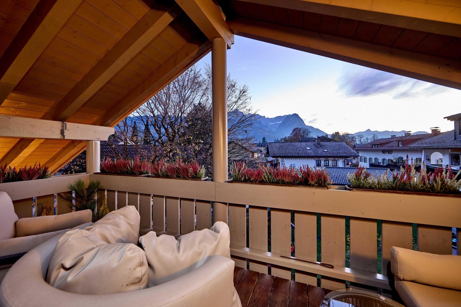 Terrasse mit Sitzgelegenheiten und Blick auf Berge und Dächer.