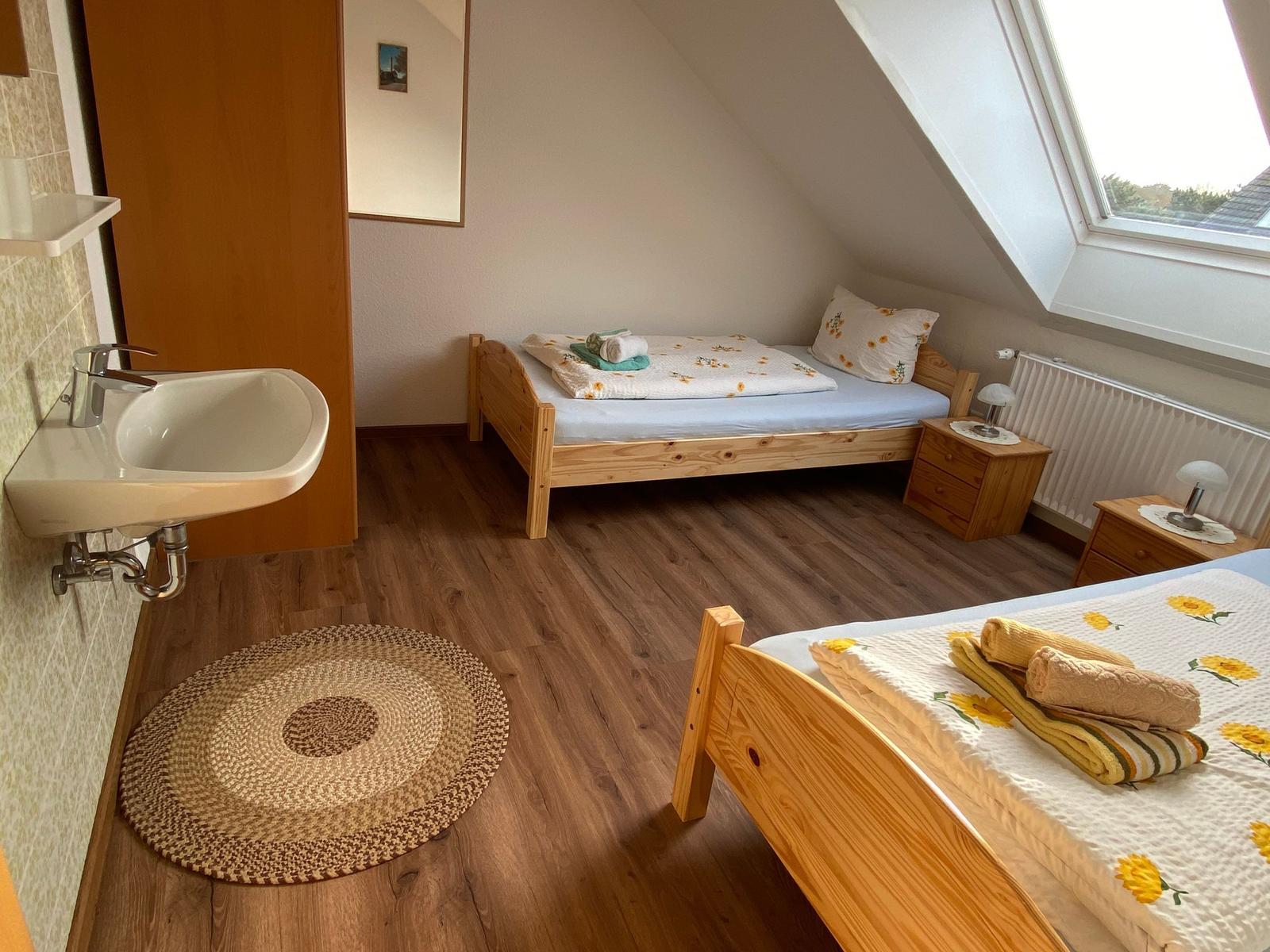 Zimmer mit zwei Betten, Dachschrägen, Dachfenster und Holzboden.