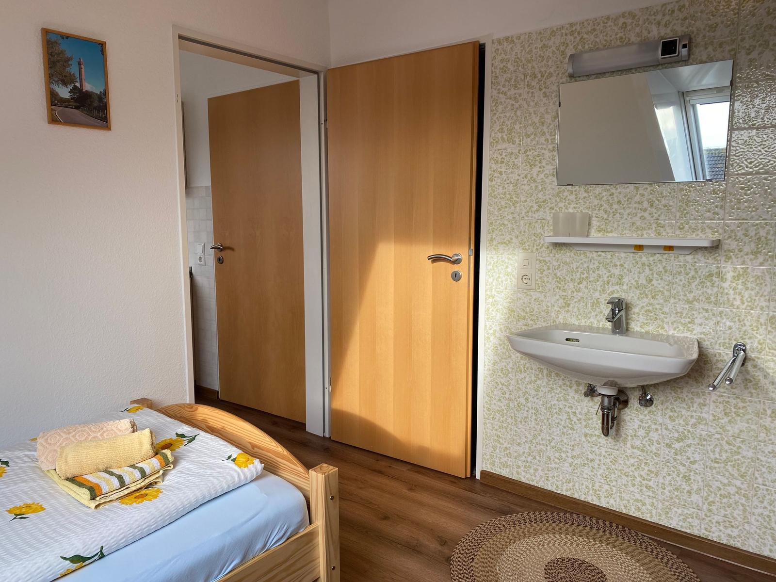 Schlafzimmer mit Bett, Bad mit Waschbecken und Spiegel