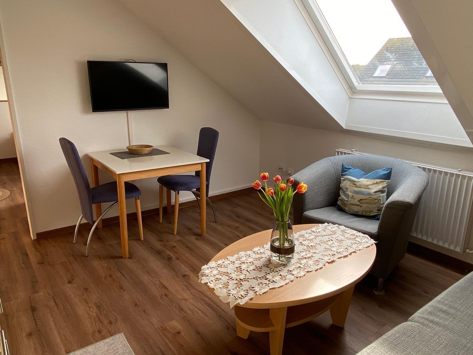 Wohnzimmer mit Esstisch, Sofa und TV unter Dachschrägen mit Dachfenster.