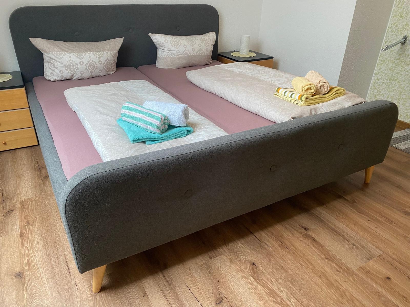 Doppelbett mit rosa Matratzen und gefalteten Handtüchern auf Holzboden.