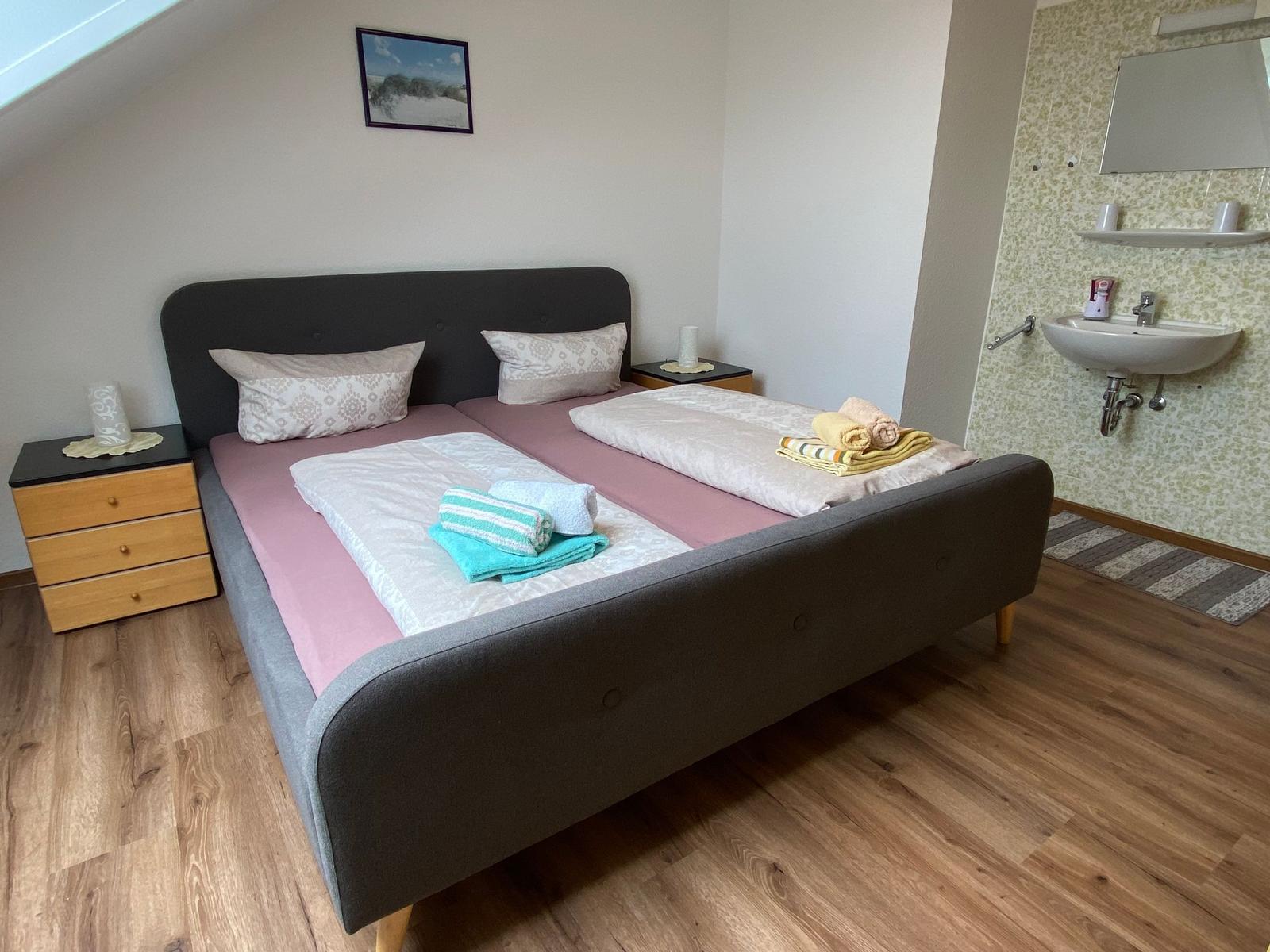 Schlafzimmer mit Doppelbett, Nachttischen und integriertem Bad mit Waschbecken.