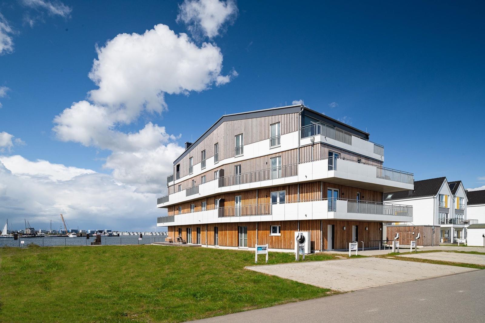 Modernes Mehrfamilienhaus mit Balkonen am Wasser.