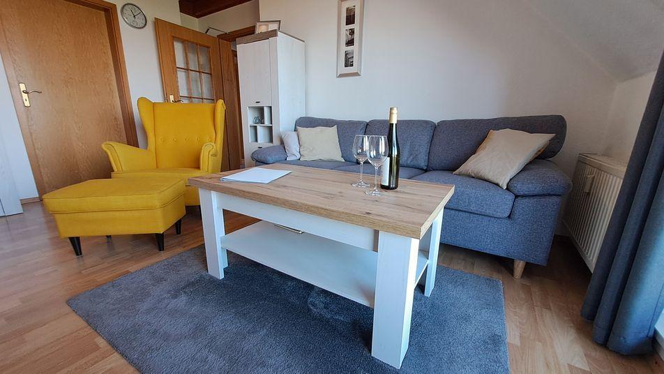 Wohnzimmer mit Sofa, gelber Sessel, Tisch und Flur