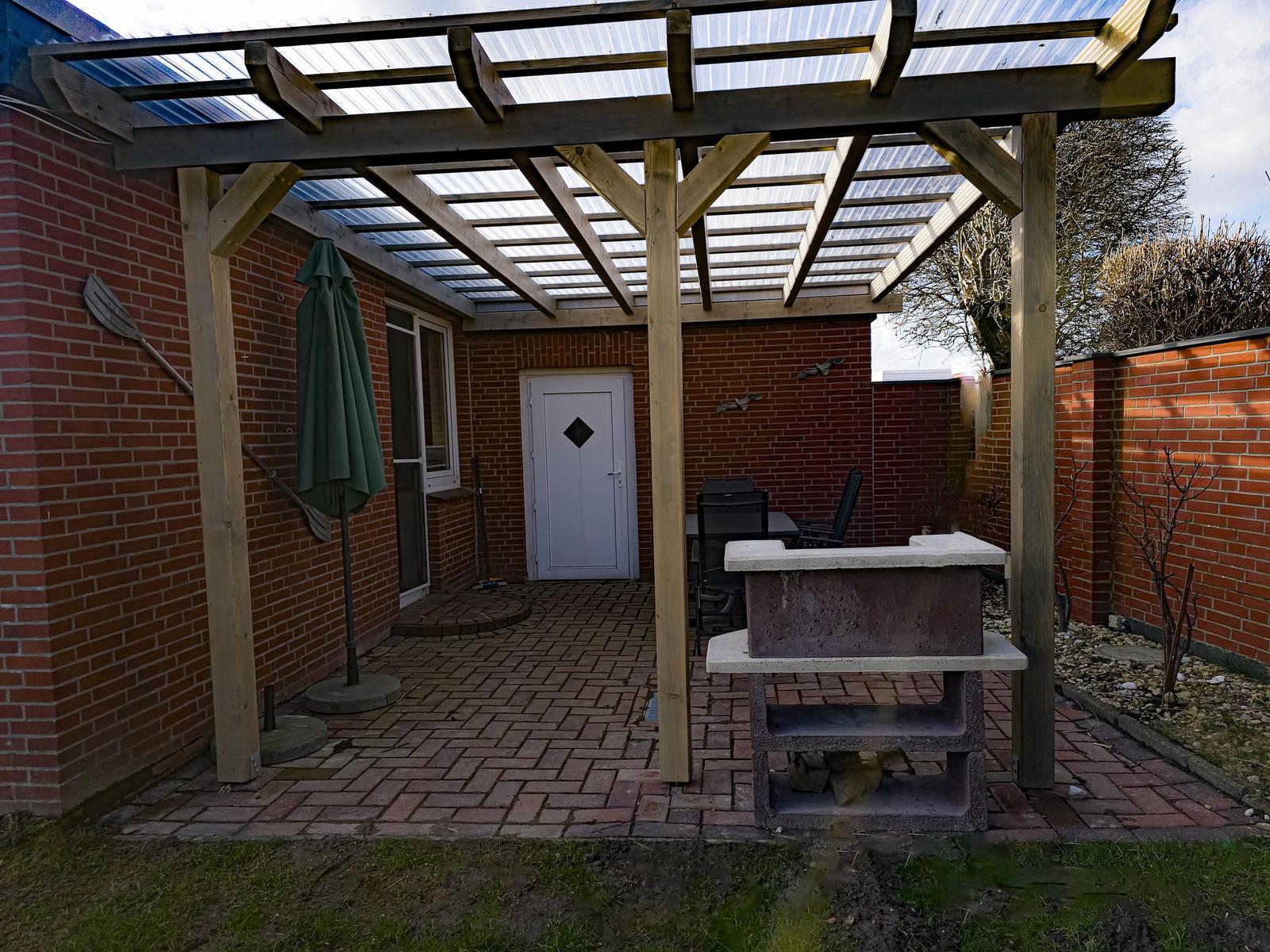 Terrace with pergola, grill, and umbrella. Backyard with brick paving and brick walls.