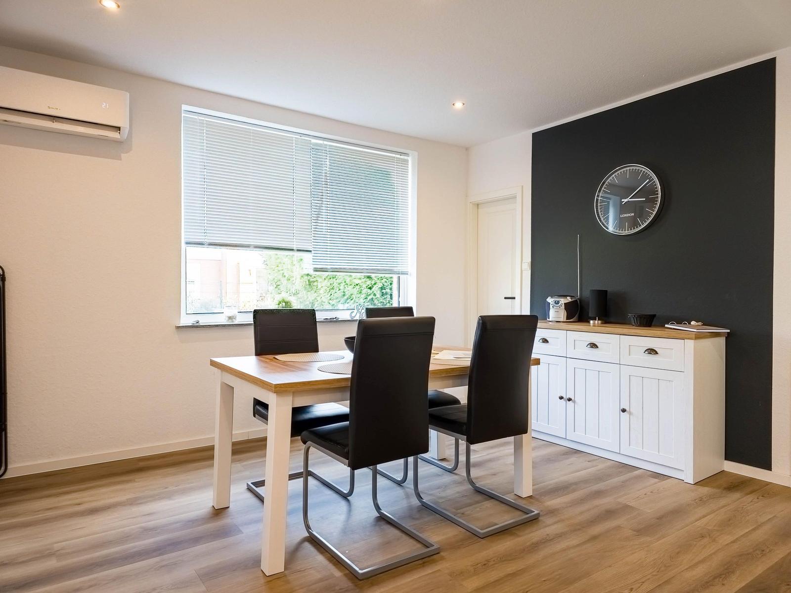 Dining room with table, chairs, window, and cabinet against black wall.