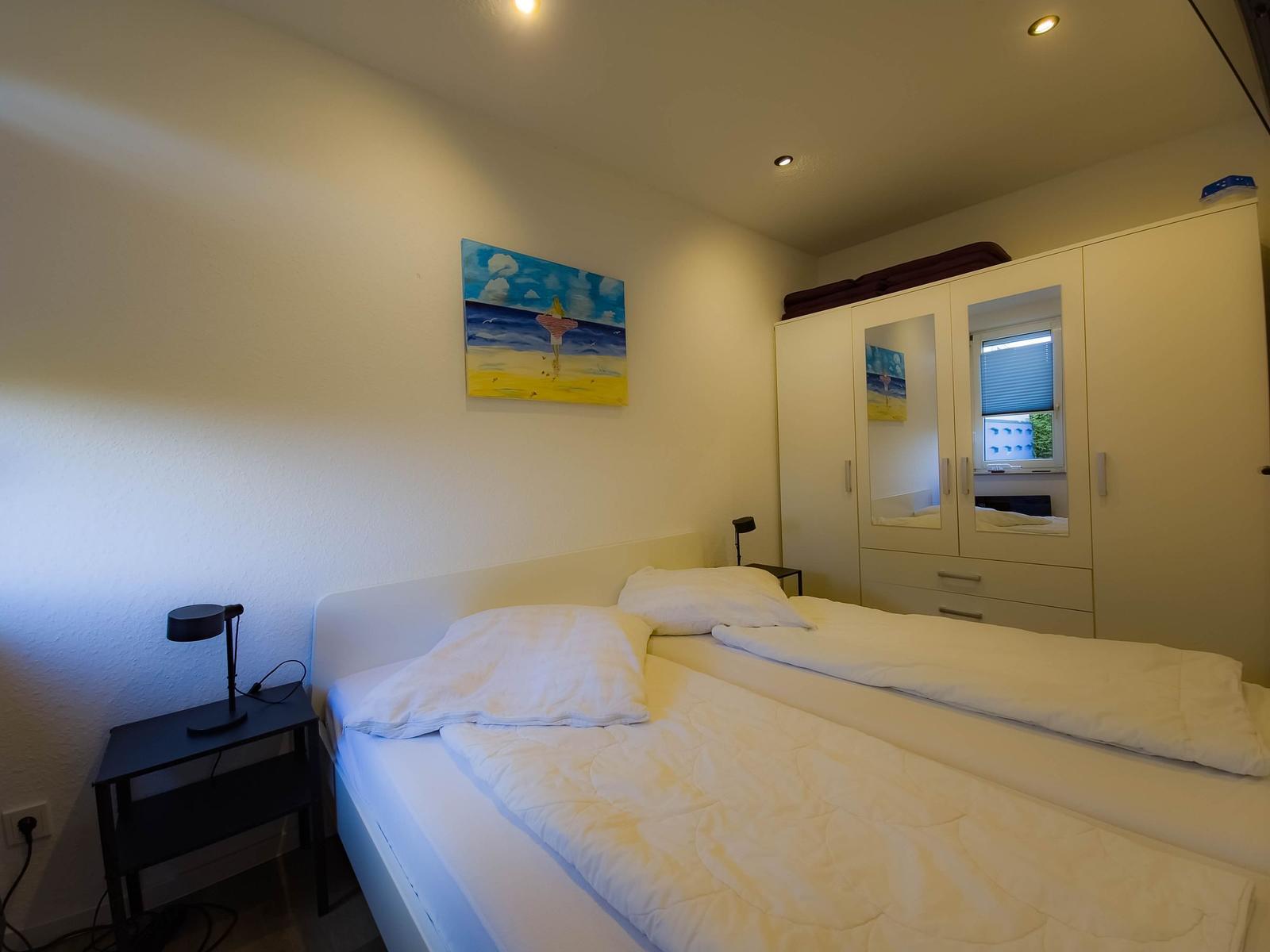 Bedroom with double bed, wardrobe, and wall art.