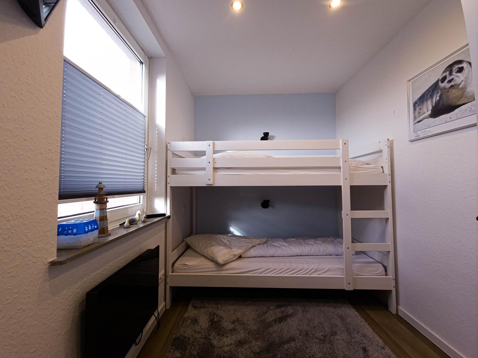Room with bunk bed, window, and wall picture.