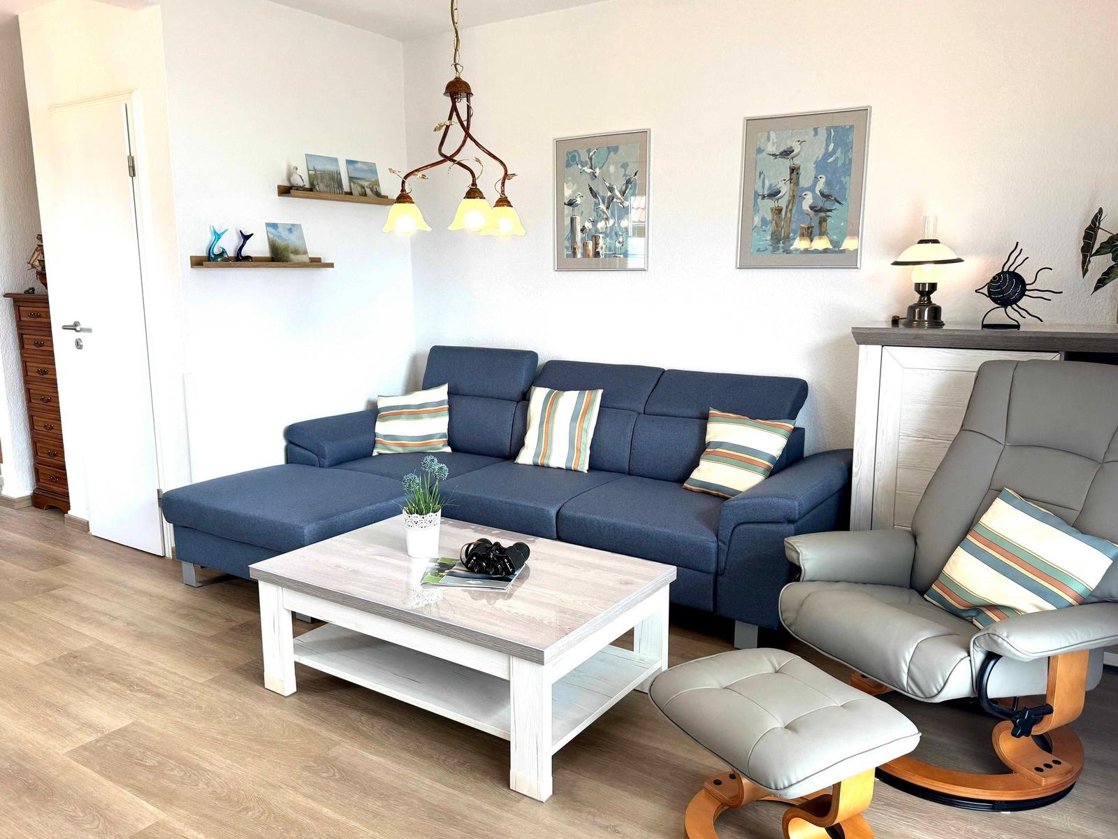 Ein Wohnzimmer mit blauem Sofa, grauem Sessel und Holzboden.