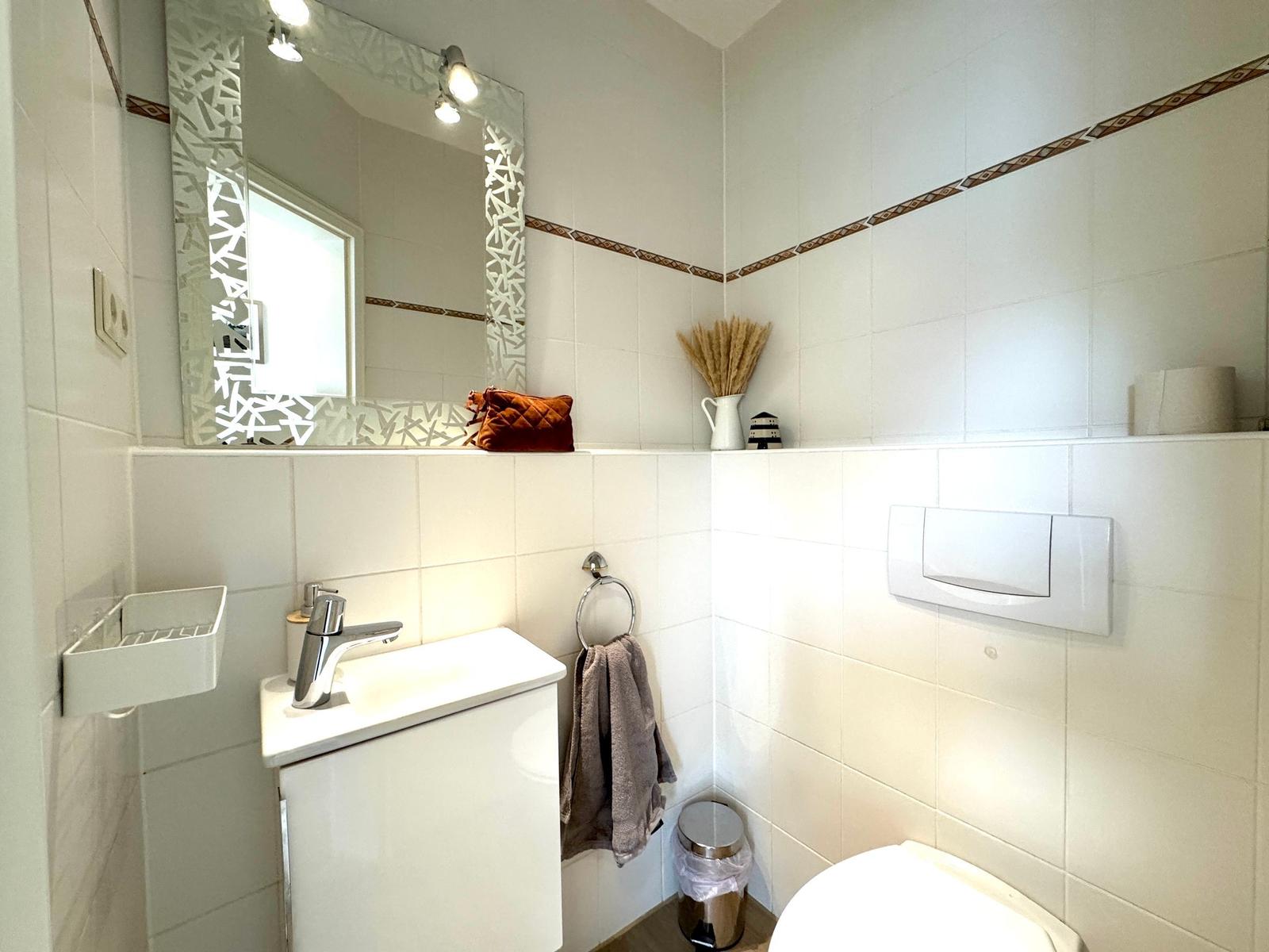 Badezimmer mit Waschbecken, Spiegel, Toilette und Handtuchhalter.