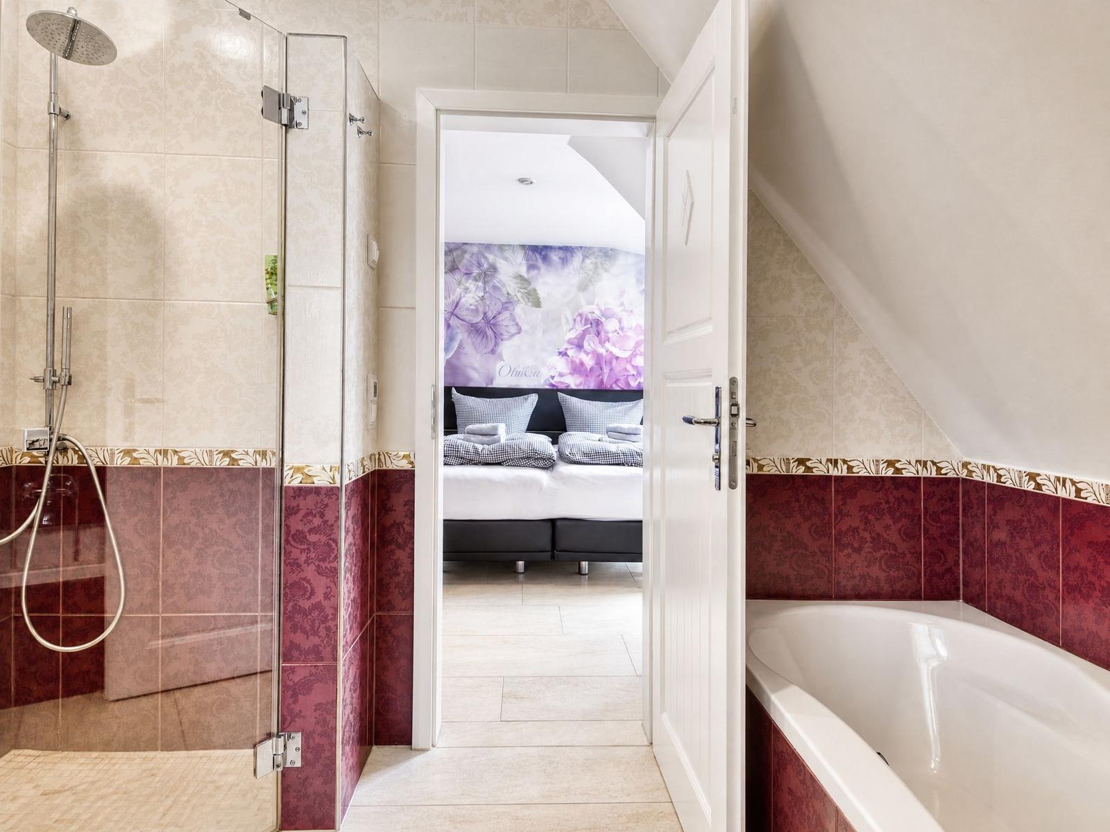 Badezimmer mit Dusche und Badewanne, Blick in Schlafzimmer mit Bett und Wandbild.
