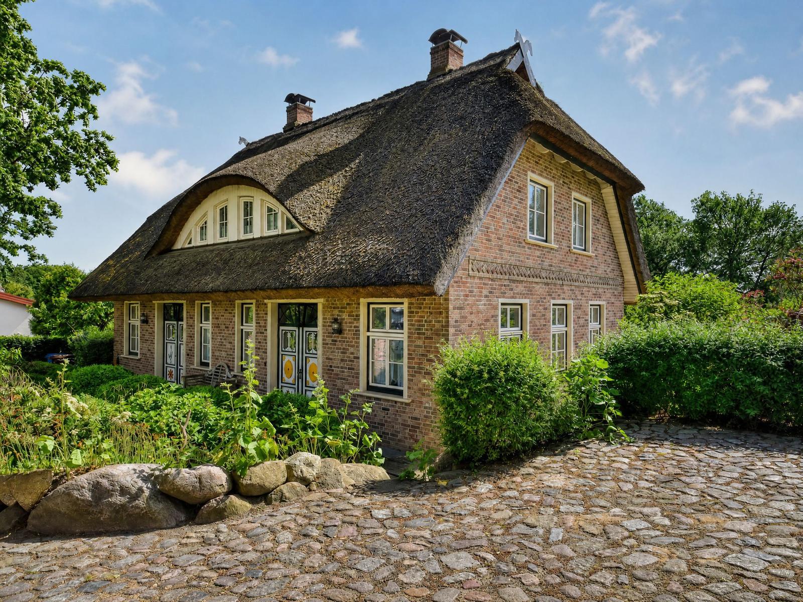 Haus mit Strohdach, Steinweg und grüner Umgebung