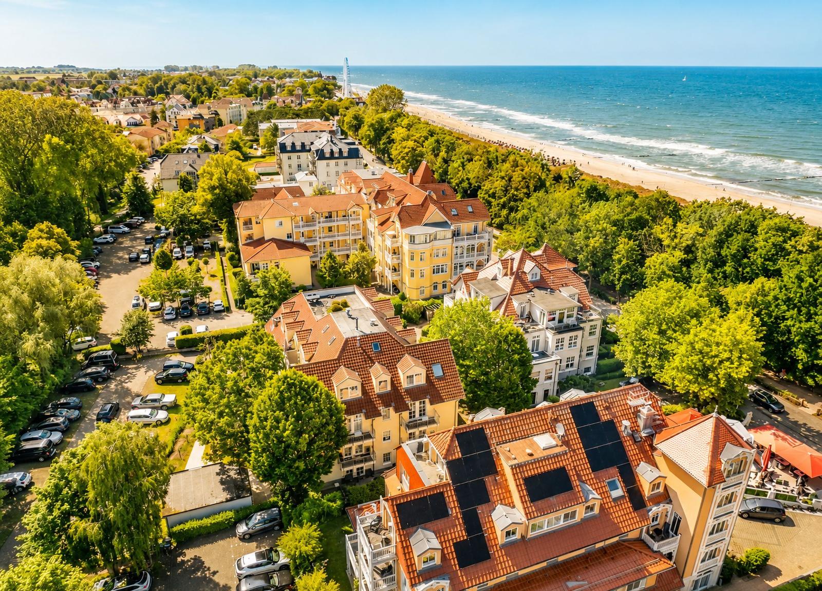 Luftbild von Hotels und Häusern am Strand mit Blick aufs Meer und einen Fahrradweg.