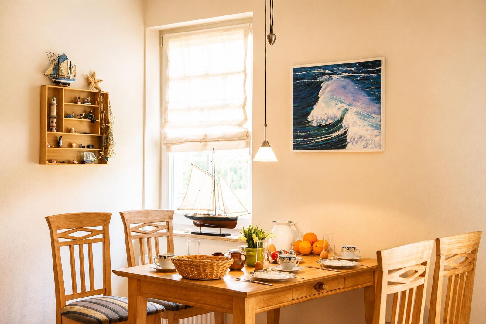 Esszimmer mit Holztisch, Stühlen und Seemotiven an der Wand.